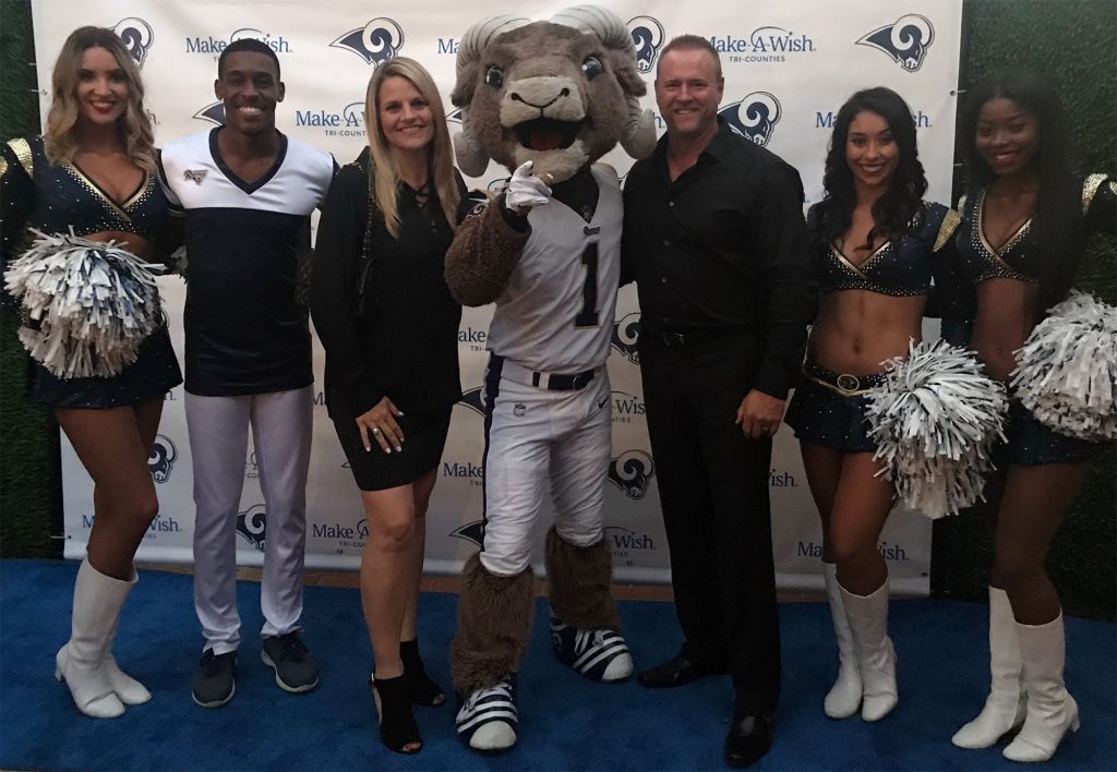 Image of Carie and Kevin Webber with players and cheerleaders from the Los Angeles Rams